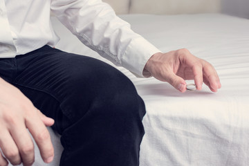 man placing wedding ring on bed