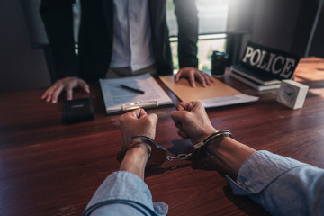man in handcuffs with police at desk