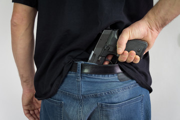 man pulling concealed gun out of waistband of pants