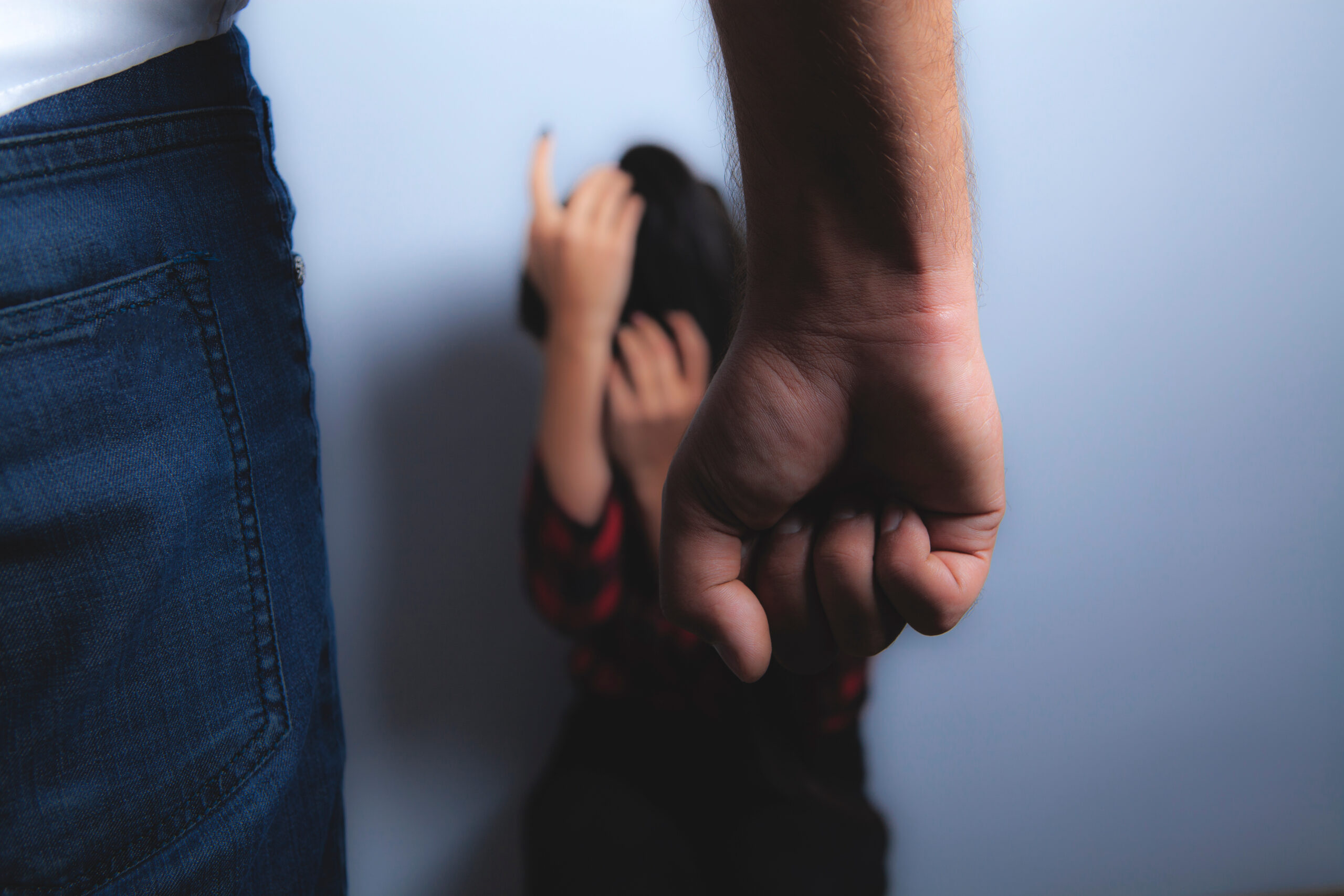 Man with clenched fist cornering girl friend on floor who is protecting her face from being struck; Montgomery County PFA Lawyer concept image