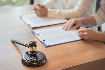couple signing prenuptial agreement with gavel and rings